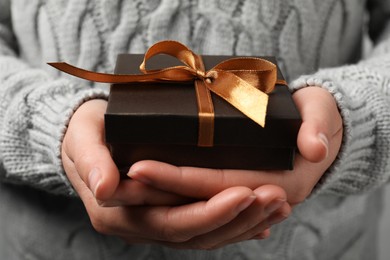 Photo of Woman holding gift box with bow as background, closeup