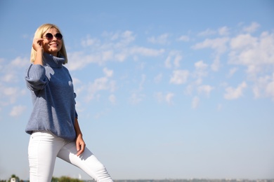 Happy woman in stylish sweater outdoors on sunny day