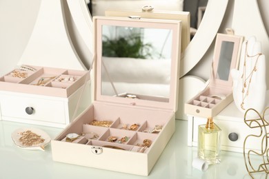 Photo of Elegant jewelry boxes with beautiful bijouterie, luxury perfume and stylish accessories on dressing table