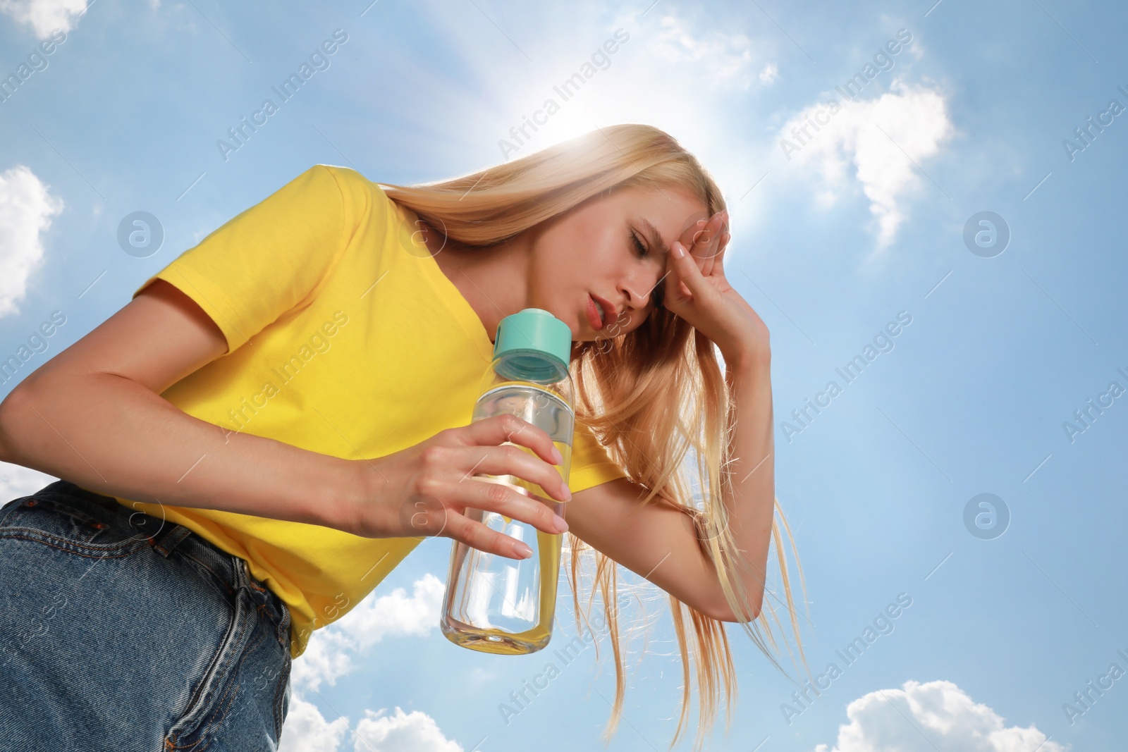 Photo of Woman with bottle of water suffering from heat stroke outdoors