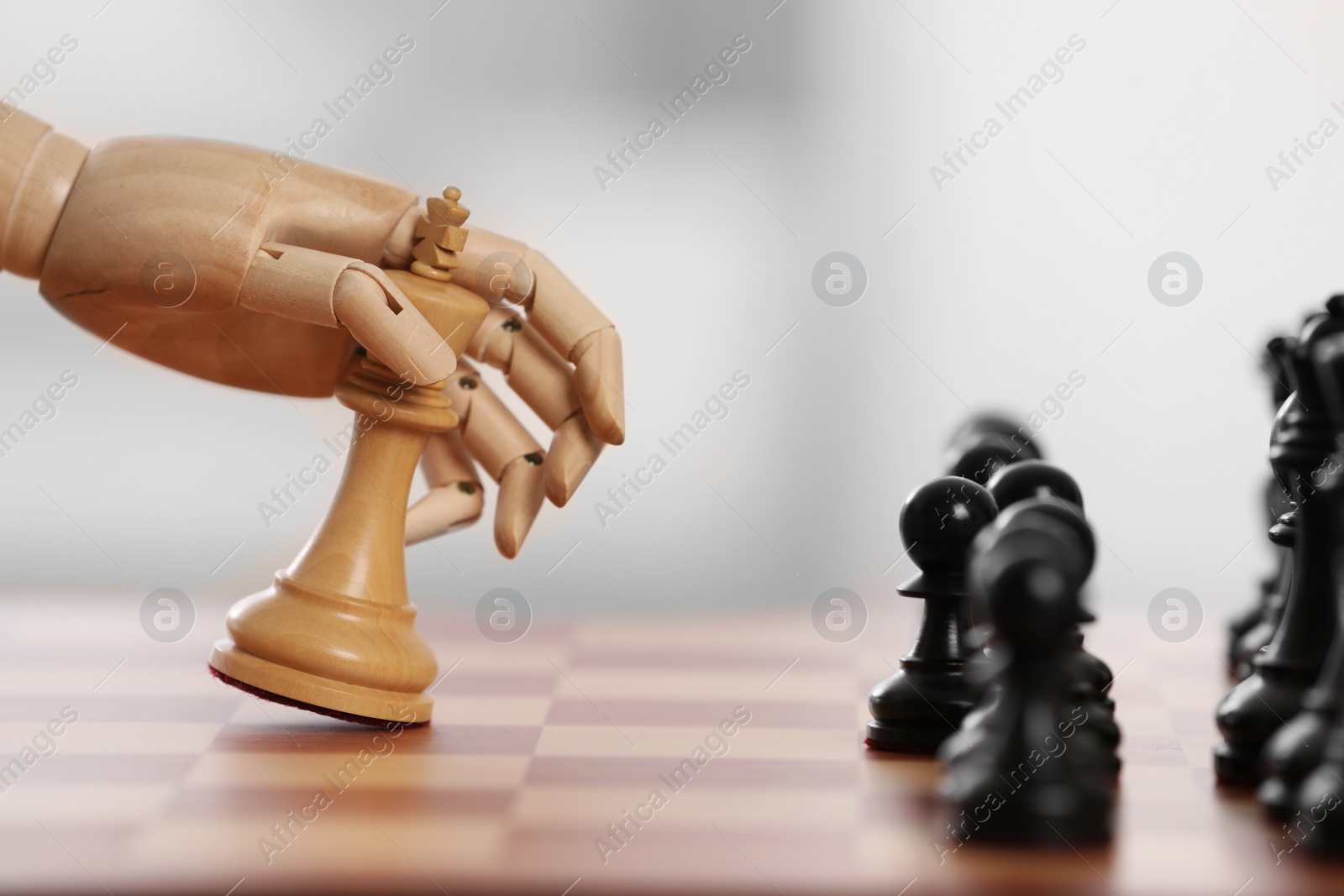 Photo of Robot moving chess piece on board against light background, closeup. Wooden hand representing artificial intelligence