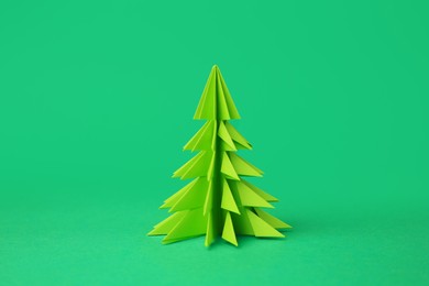 Origami art. Handmade paper Christmas tree on green background