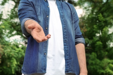 Photo of Man giving helping hand on blurred background outdoors