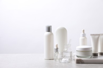Organic cosmetic products and laboratory glassware on white table, space for text