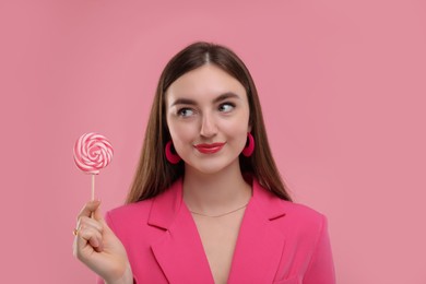 Pink look. Beautiful woman with lollipop on color background