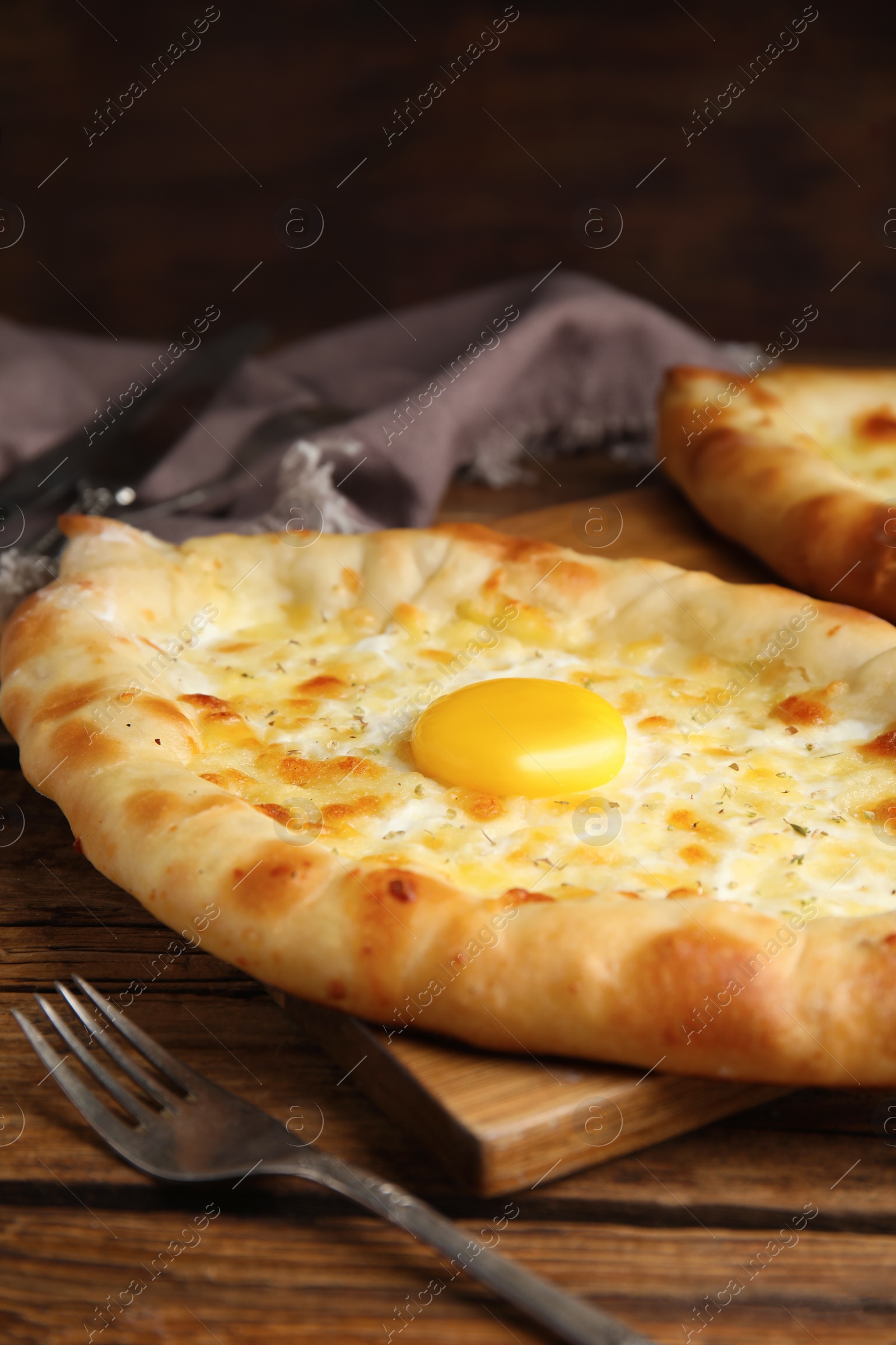 Photo of Fresh homemade khachapuri with cheese and egg on wooden table, closeup