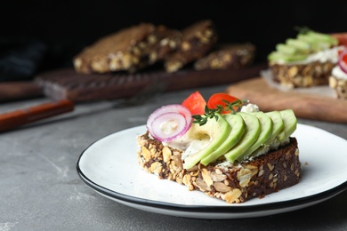 Plate with delicious avocado sandwich on grey table