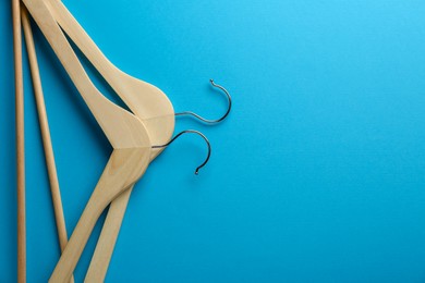 Photo of Wooden hangers on light blue background, top view. Space for text