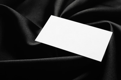 Photo of Blank business card on black fabric, closeup. Mockup for design