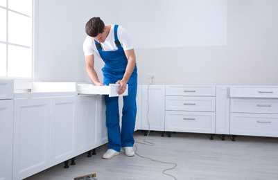 Photo of Worker installing drawer of cabinet in kitchen
