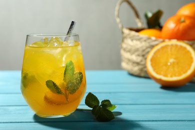 Photo of Delicious orange soda water on light blue wooden table. Space for text