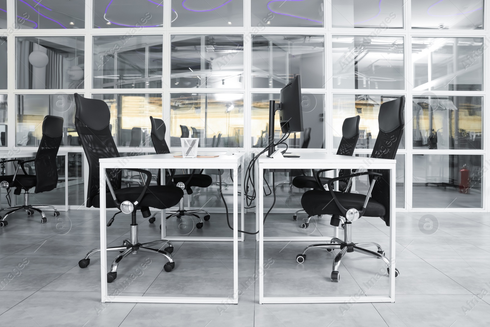 Photo of Stylish interior of open plan office. Workspace with computers, tables and chairs