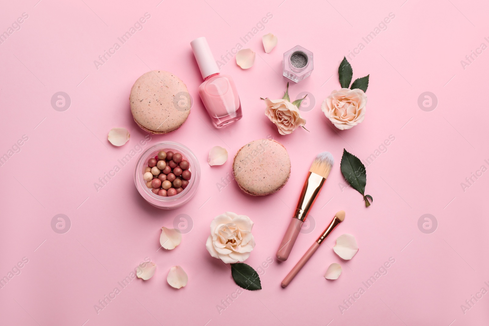 Photo of Flat lay composition with makeup products, roses and macarons on pink background