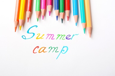Photo of Colorful pencils and words SUMMER CAMP on white background, top view