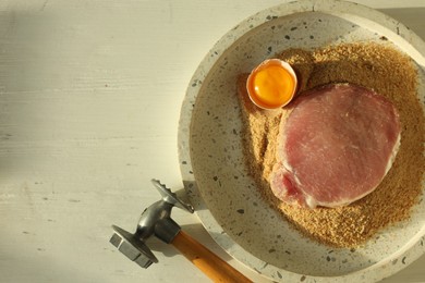 Photo of Cooking schnitzel. Raw pork chop, meat mallet and ingredients on white wooden table, flat lay. Space for text