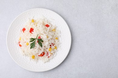 Photo of Delicious rice with vegetables and parsley on light gray table, top view. Space for text