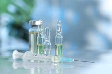 Photo of Glass vial, ampoules and syringe on white table, closeup. Space for text