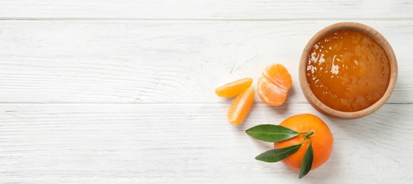 Photo of Flat lay composition with tasty tangerine jam on white wooden table. Space for text