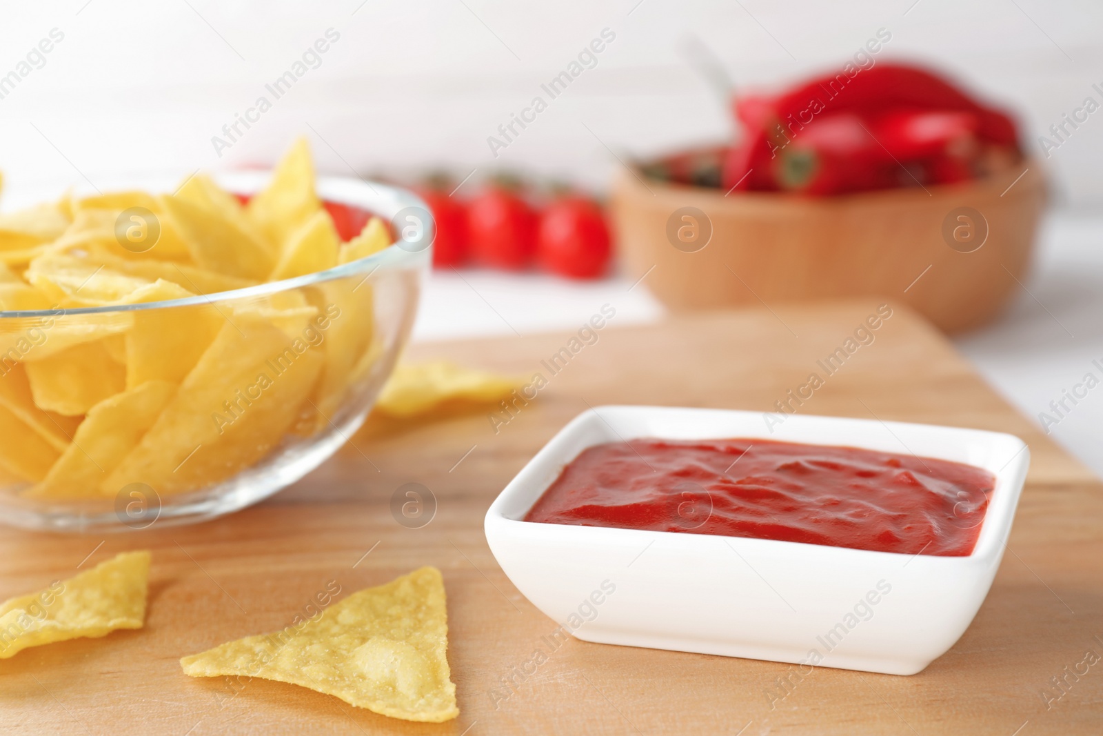 Photo of Bowl with spicy chili sauce and chips on table