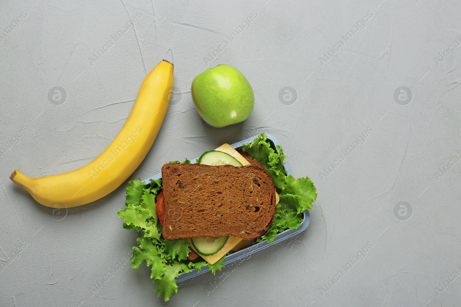 Photo of Lunch box with tasty sandwich and fruits on grey background, top view