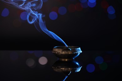 Photo of Blown out diya on dark background with blurred lights. Diwali lamp