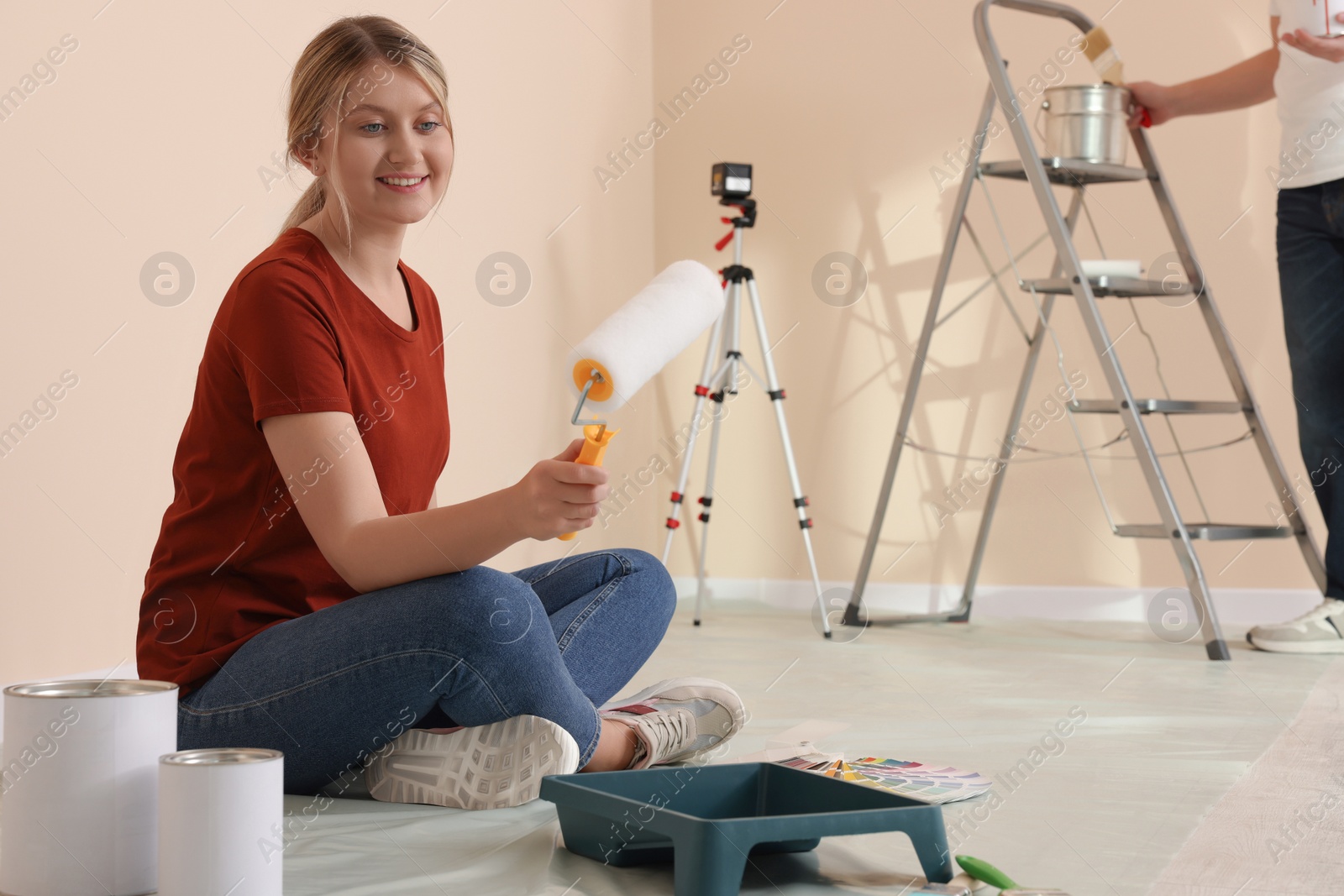 Photo of Happy couple with painting tools in apartment during repair