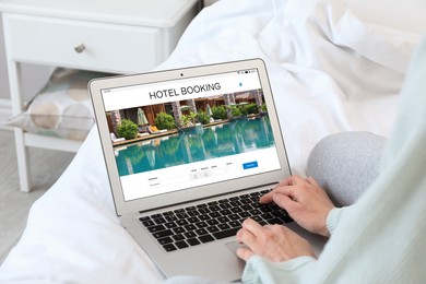 Image of Woman using laptop to book hotel at home, closeup