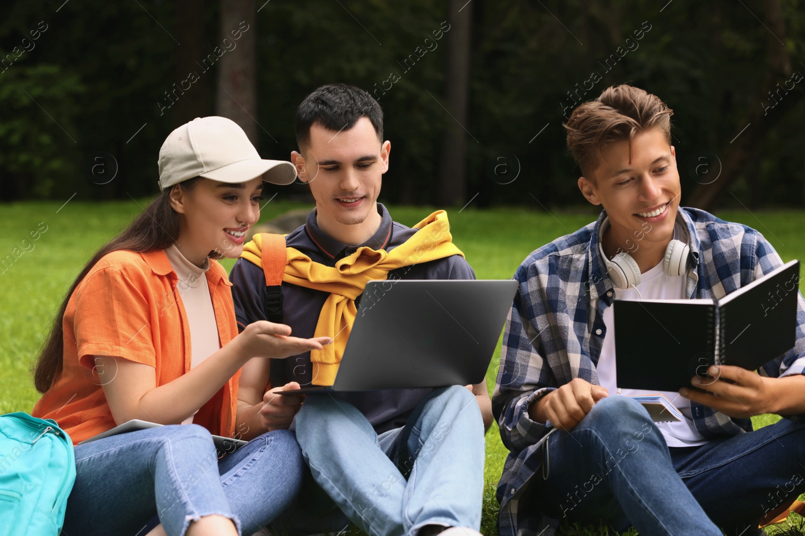 Photo of Happy young students learning together on green grass in park