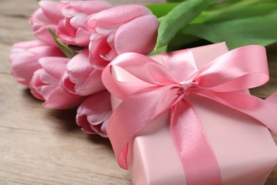 Photo of Gift box and beautiful tulip flowers on table, closeup