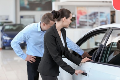 Young saleswoman working with client in car dealership