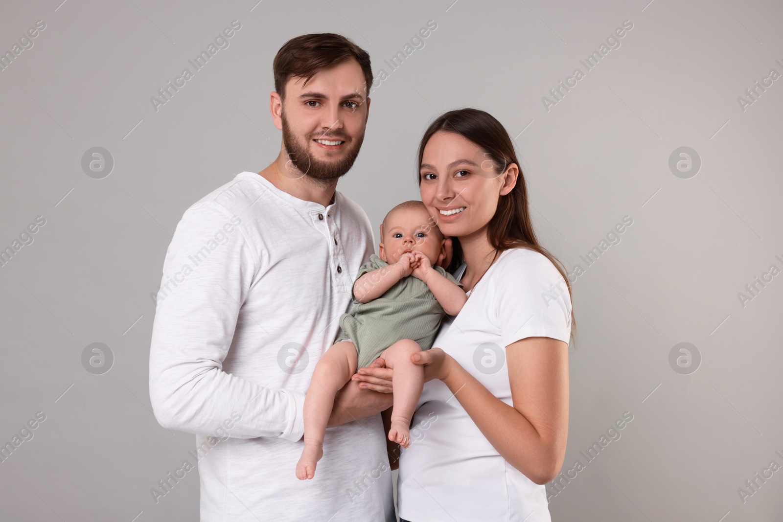 Photo of Happy family. Parents with their cute baby on grey background