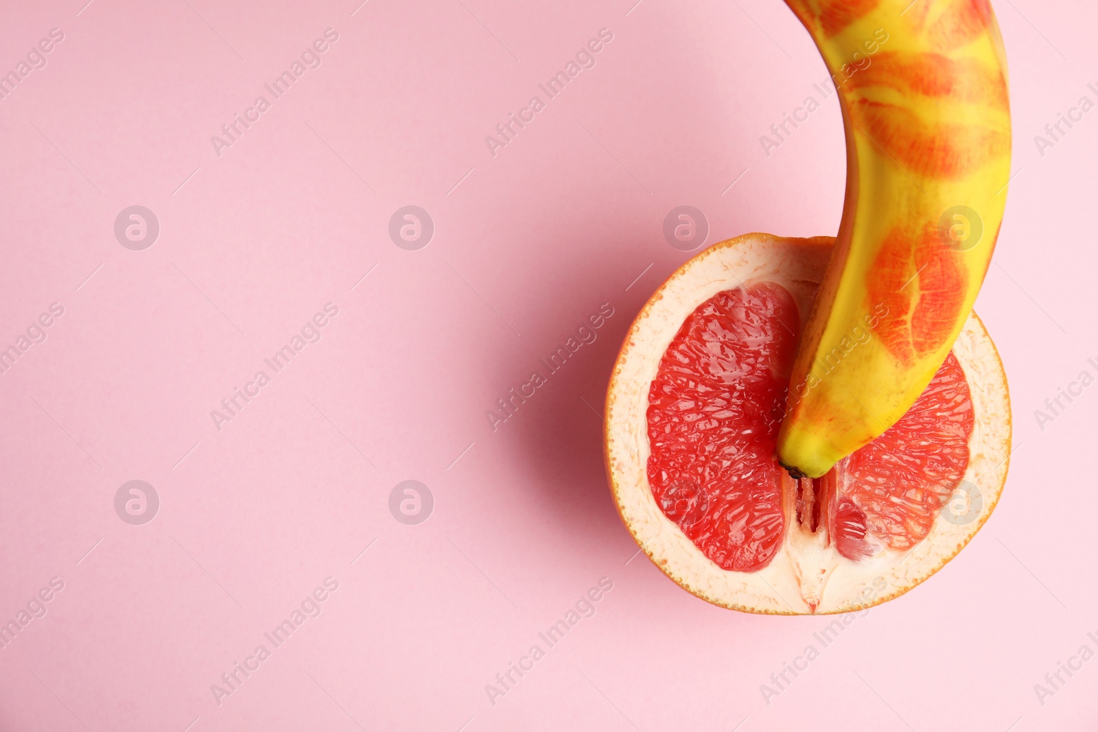 Photo of Flat lay composition with fresh banana and grapefruit on pink background, space for text. Sex concept