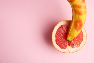 Flat lay composition with fresh banana and grapefruit on pink background, space for text. Sex concept