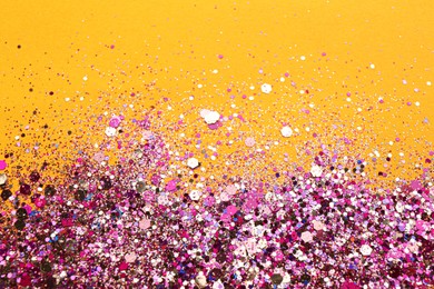 Photo of Shiny bright pink glitter on orange background. Space for text