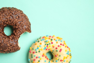 Photo of Delicious glazed donuts on turquoise background, flat lay. Space for text