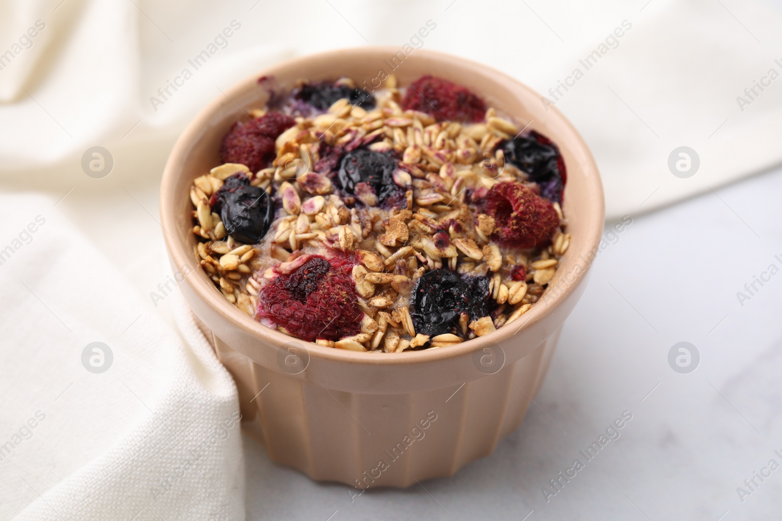 Photo of Tasty baked oatmeal with berries on white table, closeup