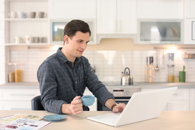 Photo of Portrait of confident young man with  laptop and cup at table