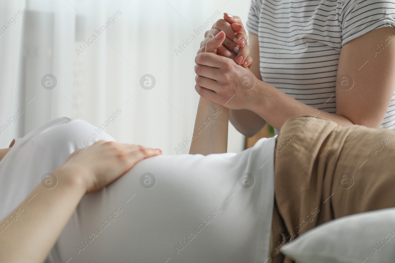 Photo of Doula taking care of pregnant woman indoors, closeup. Preparation for child birth