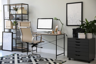 Photo of Comfortable office chair near desk with modern computer indoors