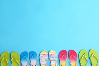 Photo of Different flip flops and space for text on blue background, flat lay. Summer beach accessories