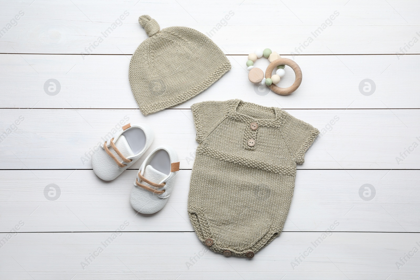 Photo of Flat lay composition with child's clothes and toys on white wooden table