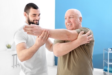 Young physiotherapist working with senior patient in clinic