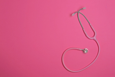 Photo of Modern stethoscope on pink background, top view. Space for text