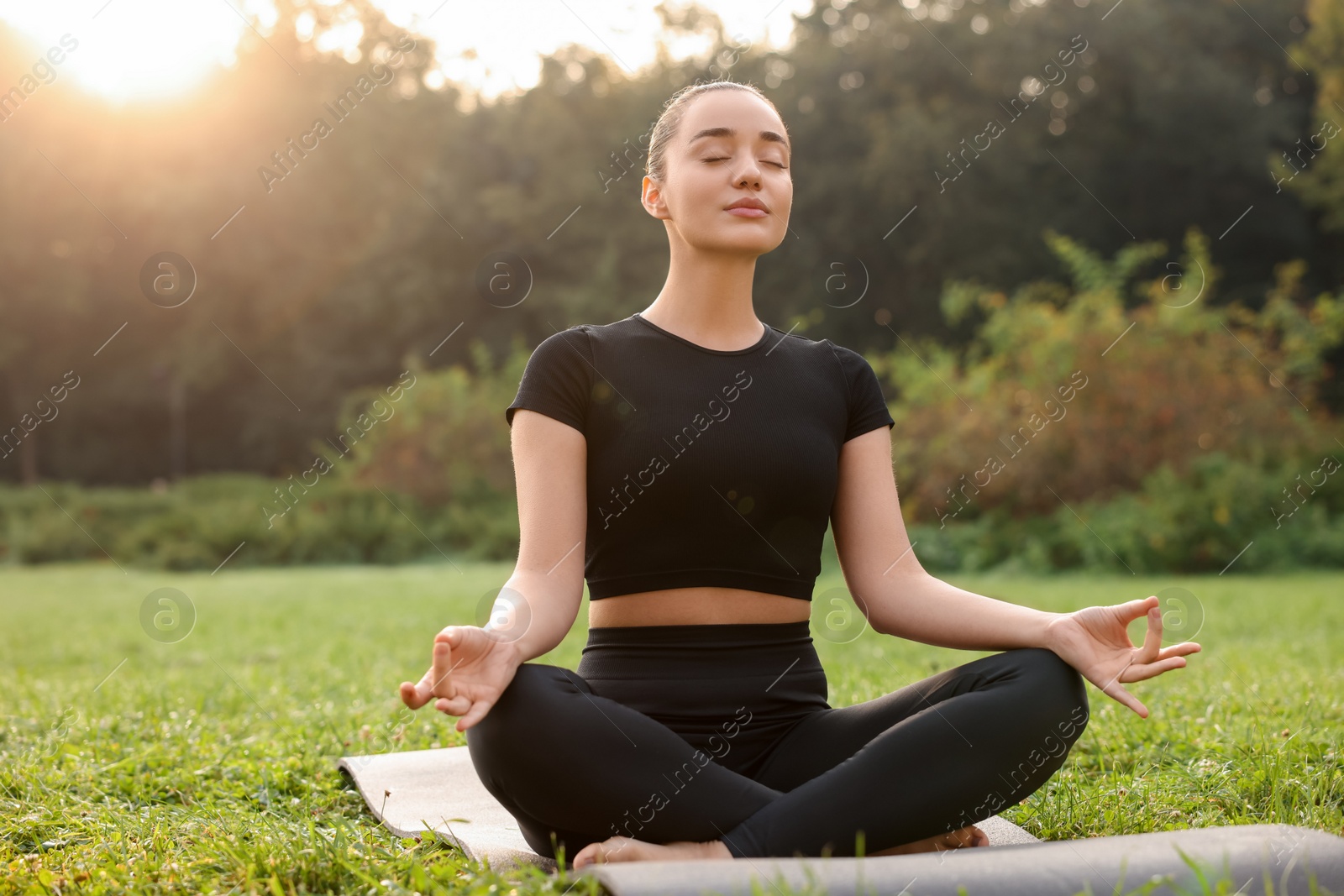 Photo of Beautiful woman practicing yoga outdoors on sunny day. Lotus pose