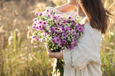 Woman holding bouquet of beautiful wild flowers outdoors, closeup