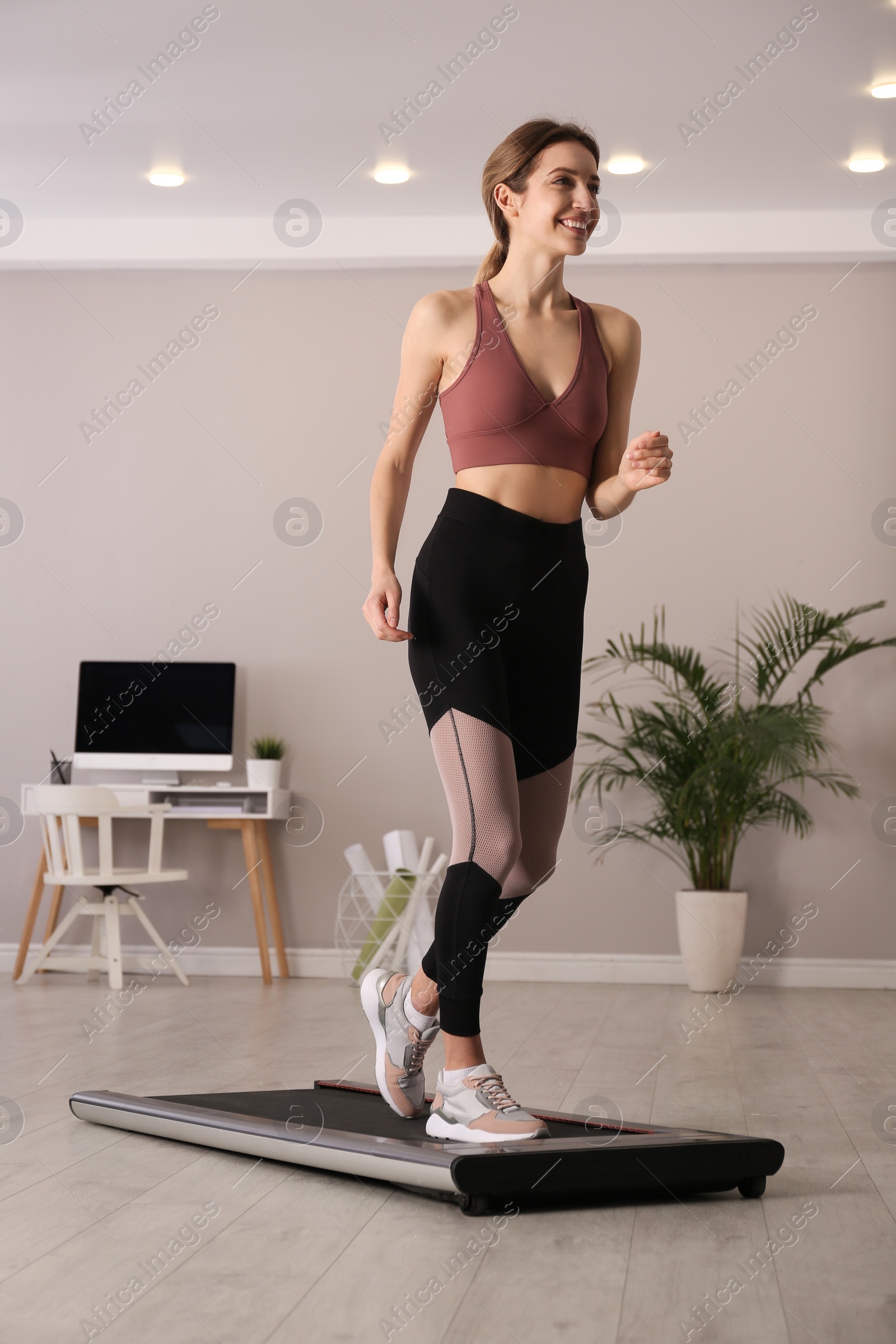 Photo of Sporty woman training on walking treadmill at home