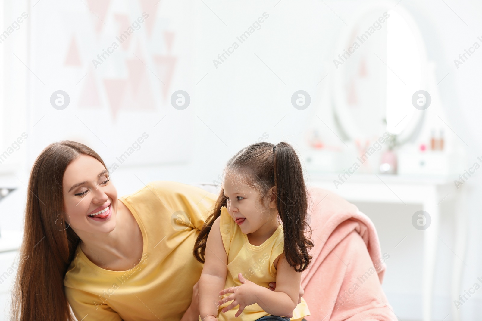 Photo of Young mother with little daughter having fun at home