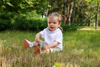 Photo of Little girl sitting on grass in park