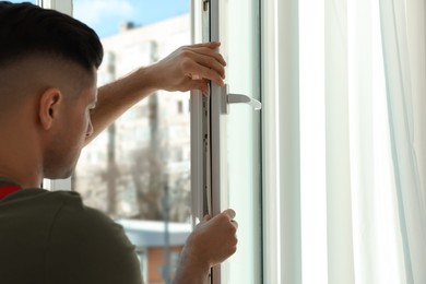 Photo of Man putting rubber draught strip onto window indoors