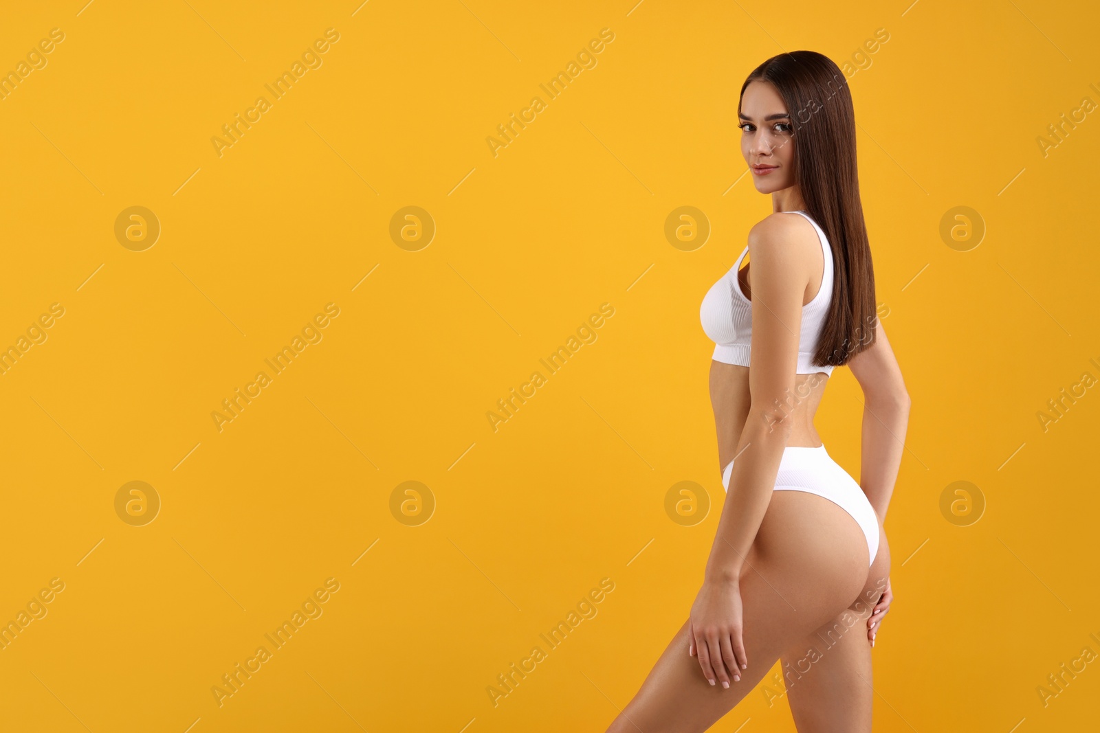 Photo of Young woman in stylish white bikini on orange background. Space for text